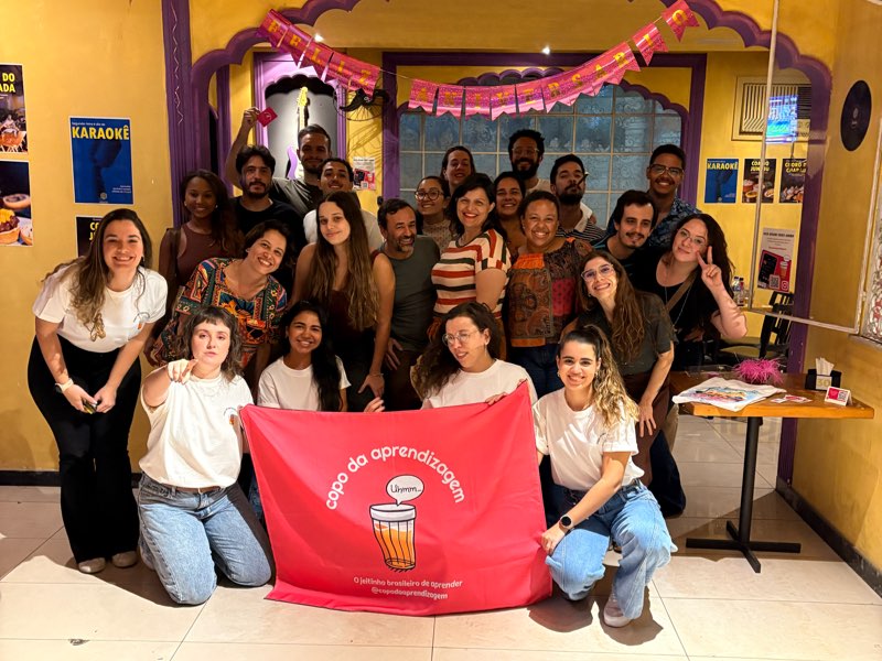 Foto do grupo inteiro segurando a bandeira rosa do Copo da Aprendizagem no fim de uma edição.